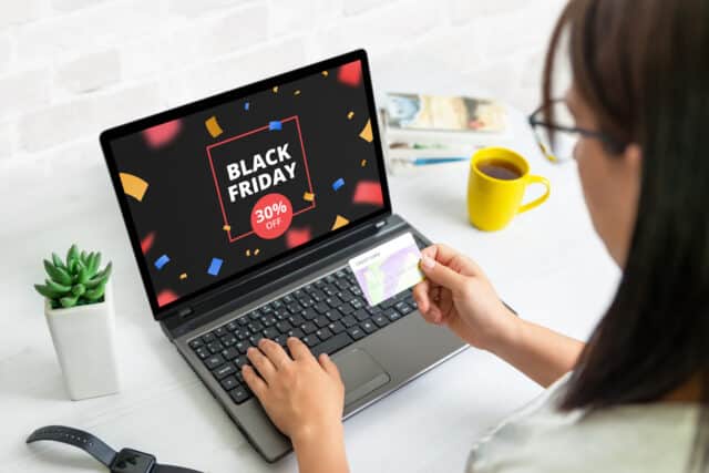 Black friday shopping online concept with discount banner on laptop display. Woman hold credit card concept